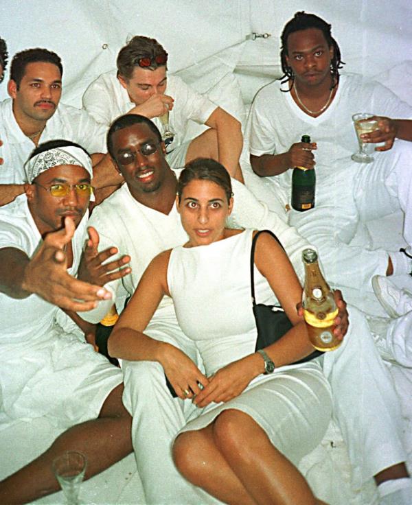 Rapper Sean Combs, known as P Diddy, hosting a White Party at his mansion with other celebrities including Q-Tip, Vincent Laresca, and Jarobi White, all dressed in white.